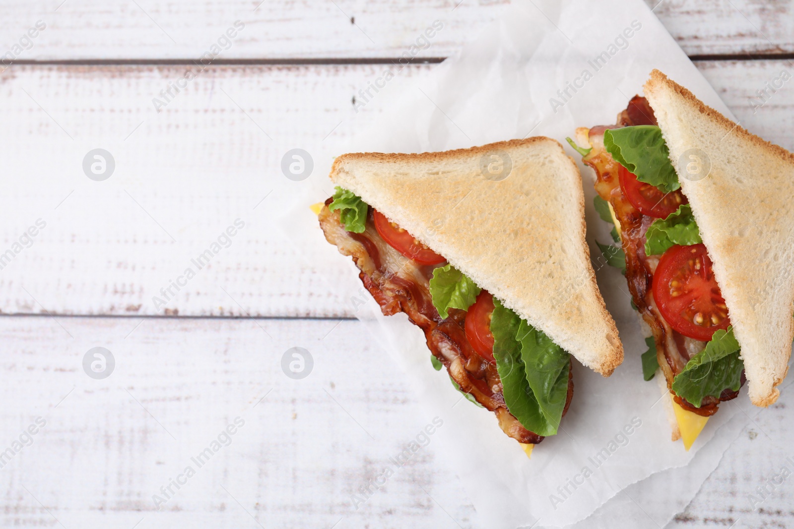 Photo of Delicious sandwiches with fried bacon on wooden rustic table, top view. Space for text