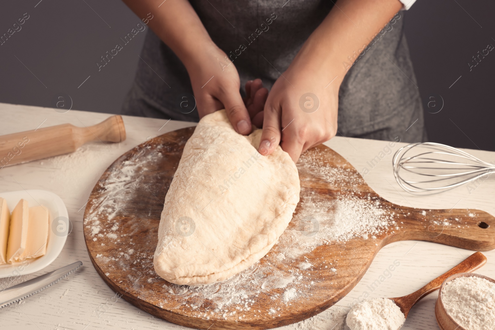 Photo of Man kneading dough at table near grey wall, closeup