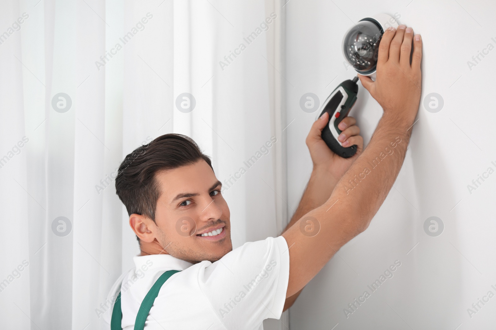 Photo of Technician installing CCTV camera on wall indoors