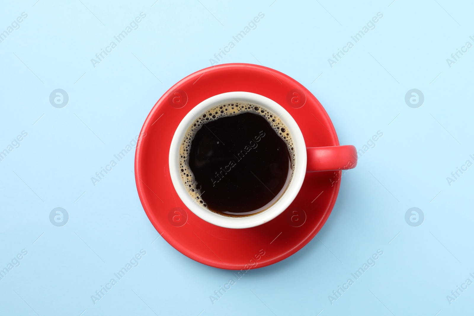 Photo of Aromatic coffee in cup on light blue background, top view