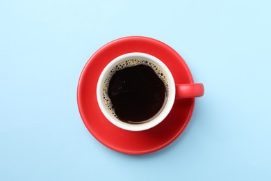 Photo of Aromatic coffee in cup on light blue background, top view