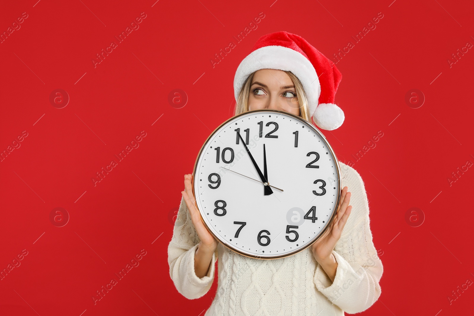 Photo of Woman in Santa hat with clock on red background, space for text. New Year countdown