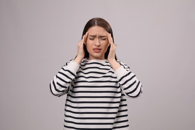 Photo of Woman suffering from headache on light grey background. Cold symptoms