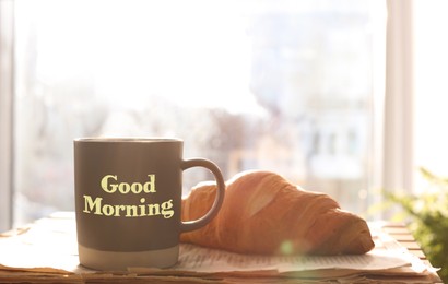 Good Morning. Delicious coffee, newspaper and croissant near window indoors