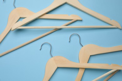 Photo of Empty clothes hangers on light blue background, flat lay