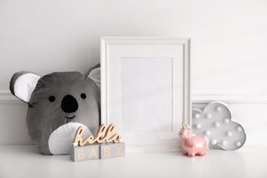 Photo of Empty photo frame, cute toy and decor near wall, space for text. Baby room interior element