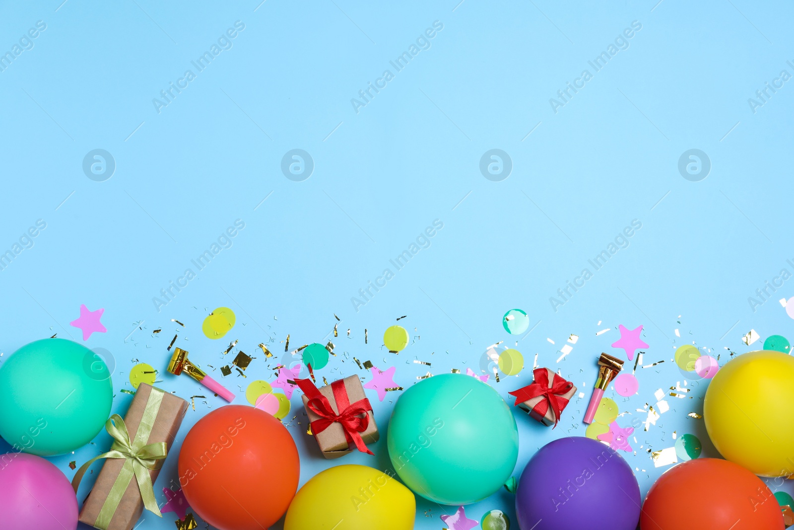 Photo of Flat lay composition with balloons and confetti on light blue background, space for text. Birthday decor