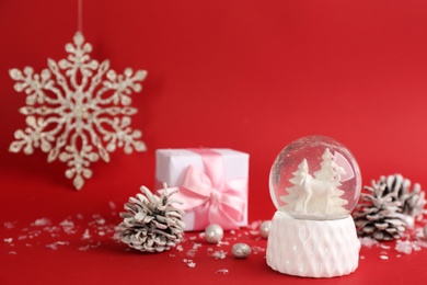 Beautiful Christmas snow globe and festive decor on red background. Space for text