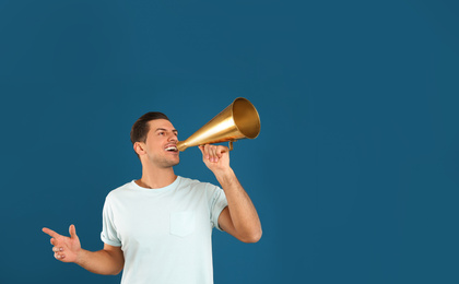 Handsome man with megaphone on blue background