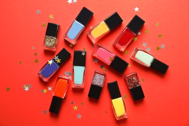 Bottles of nail polish on color background, top view