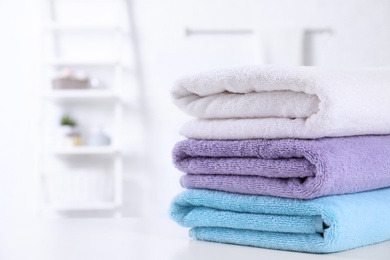 Stack of fresh towels on table in bathroom. Space for text