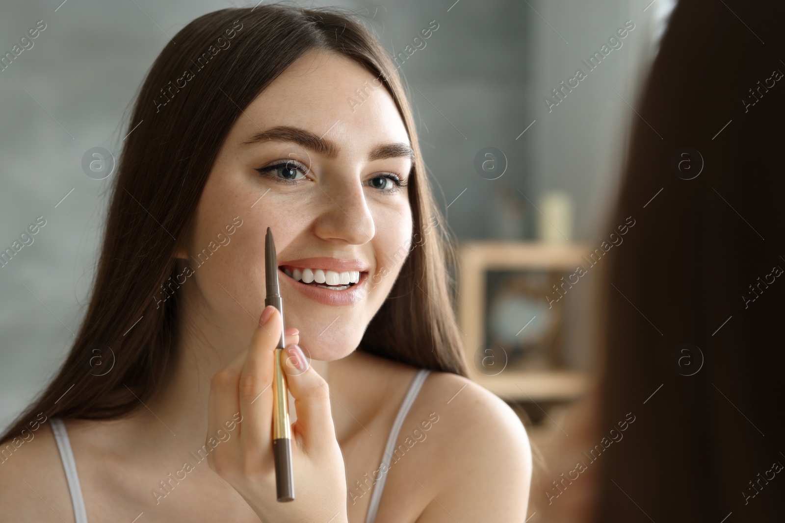 Photo of Smiling woman drawing freckles with pen indoors