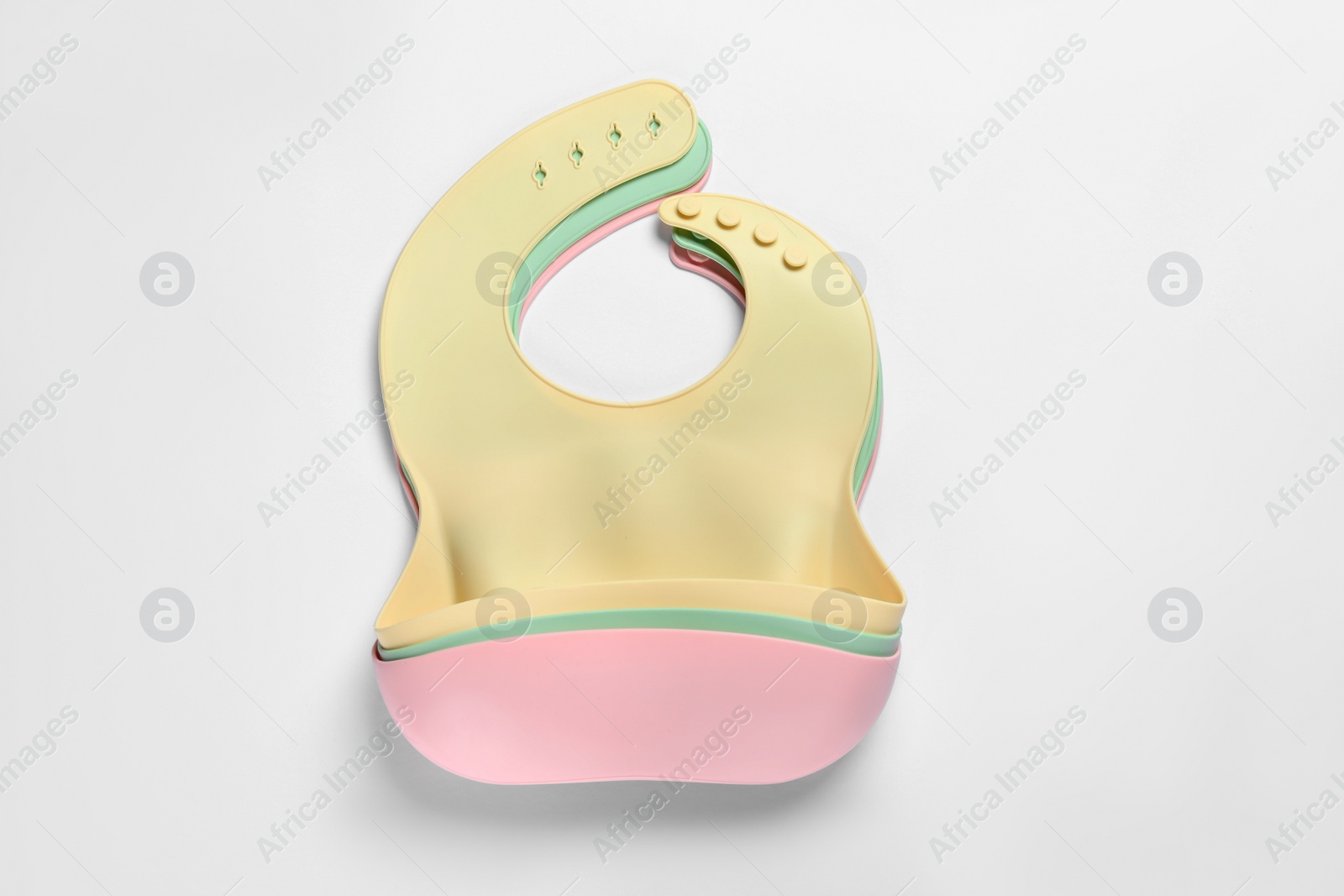 Photo of Color silicone baby bibs on white background, top view