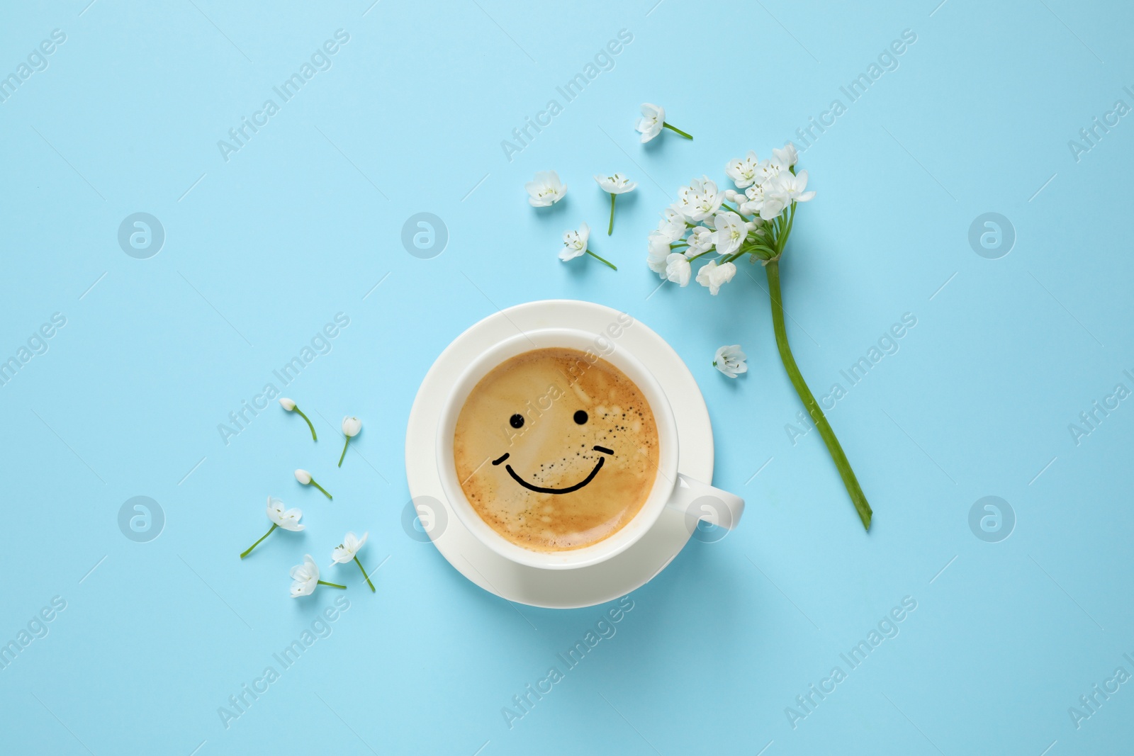 Image of Coffee with happy face and flowers on light blue background, flat lay. Good morning