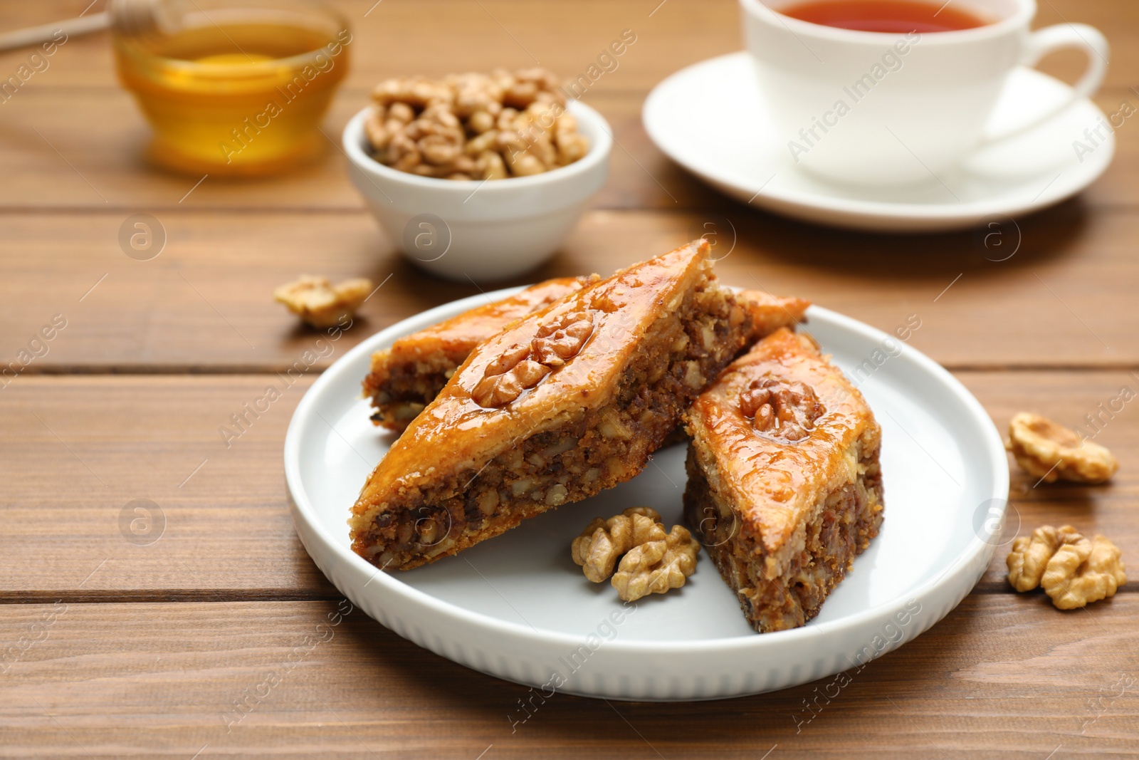 Photo of Delicious honey baklava with walnuts served on wooden table