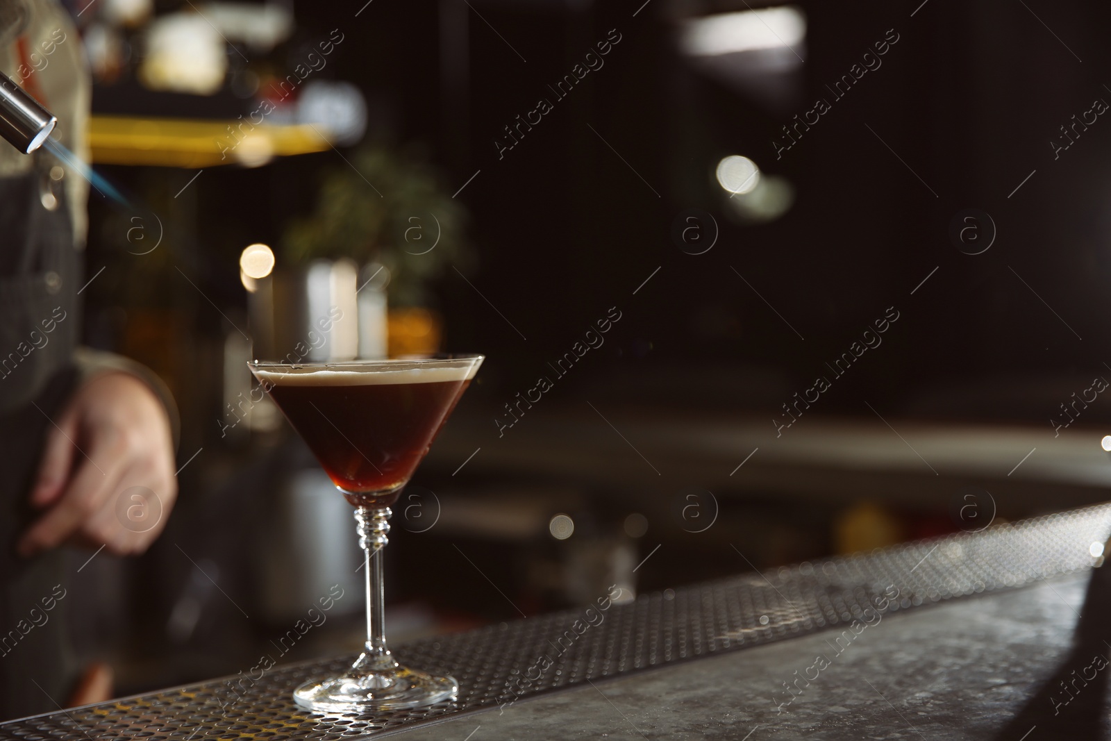 Photo of Barman preparing espresso martini cocktail with gas torch at counter, closeup. Space for text