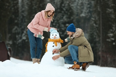 Photo of Couple making snowman outdoors. Winter vacation