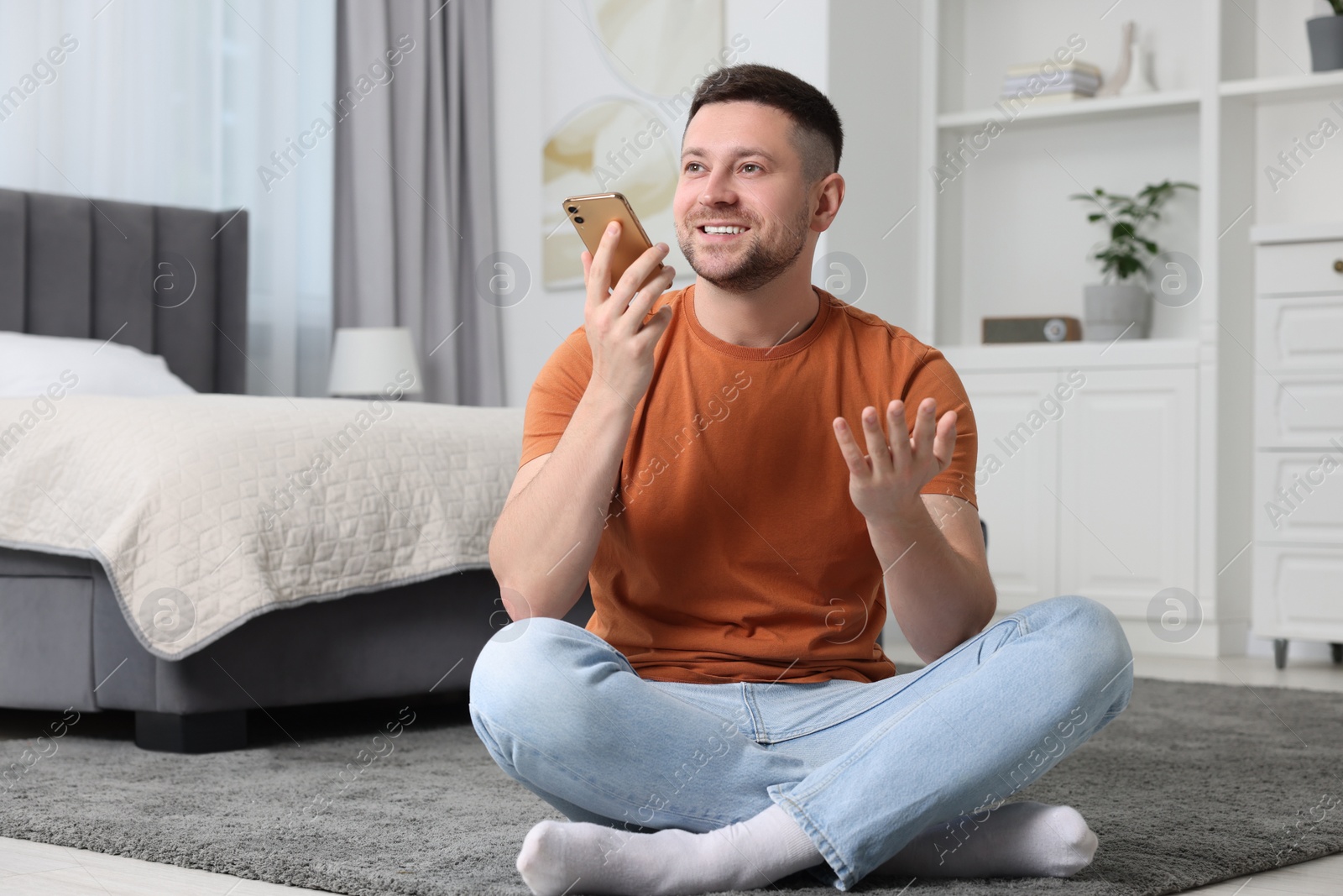 Photo of Handsome man recording voice message via smartphone at home