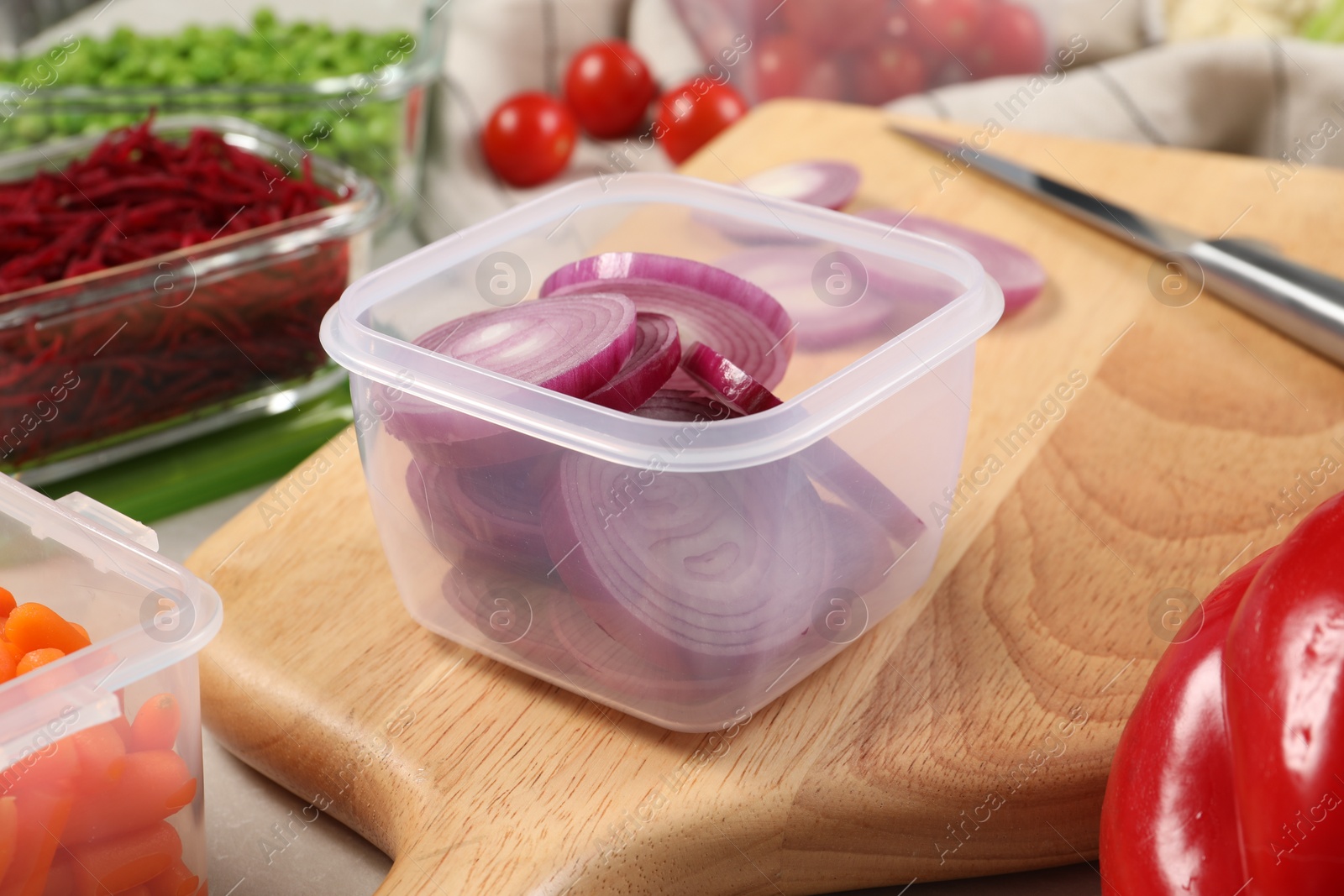 Photo of Containers with cut onion and fresh products on table. Food storage