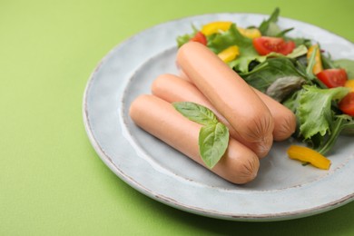 Photo of Delicious boiled sausages with salad on green