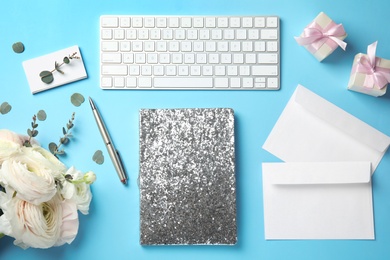 Flat lay composition with glittering notebook, keyboard and spring flowers on color background