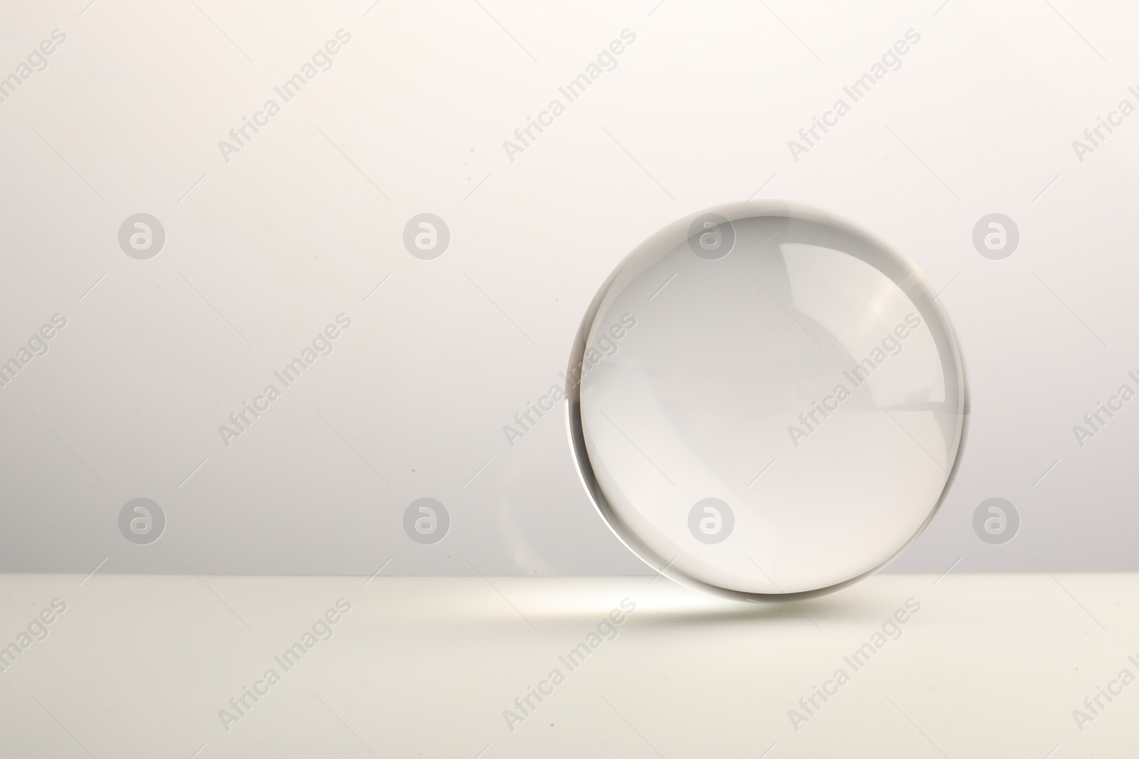 Photo of Transparent glass ball on white background. Space for text