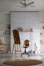 Photo of Modern studio interior with wooden easel and chair. Artist's workplace