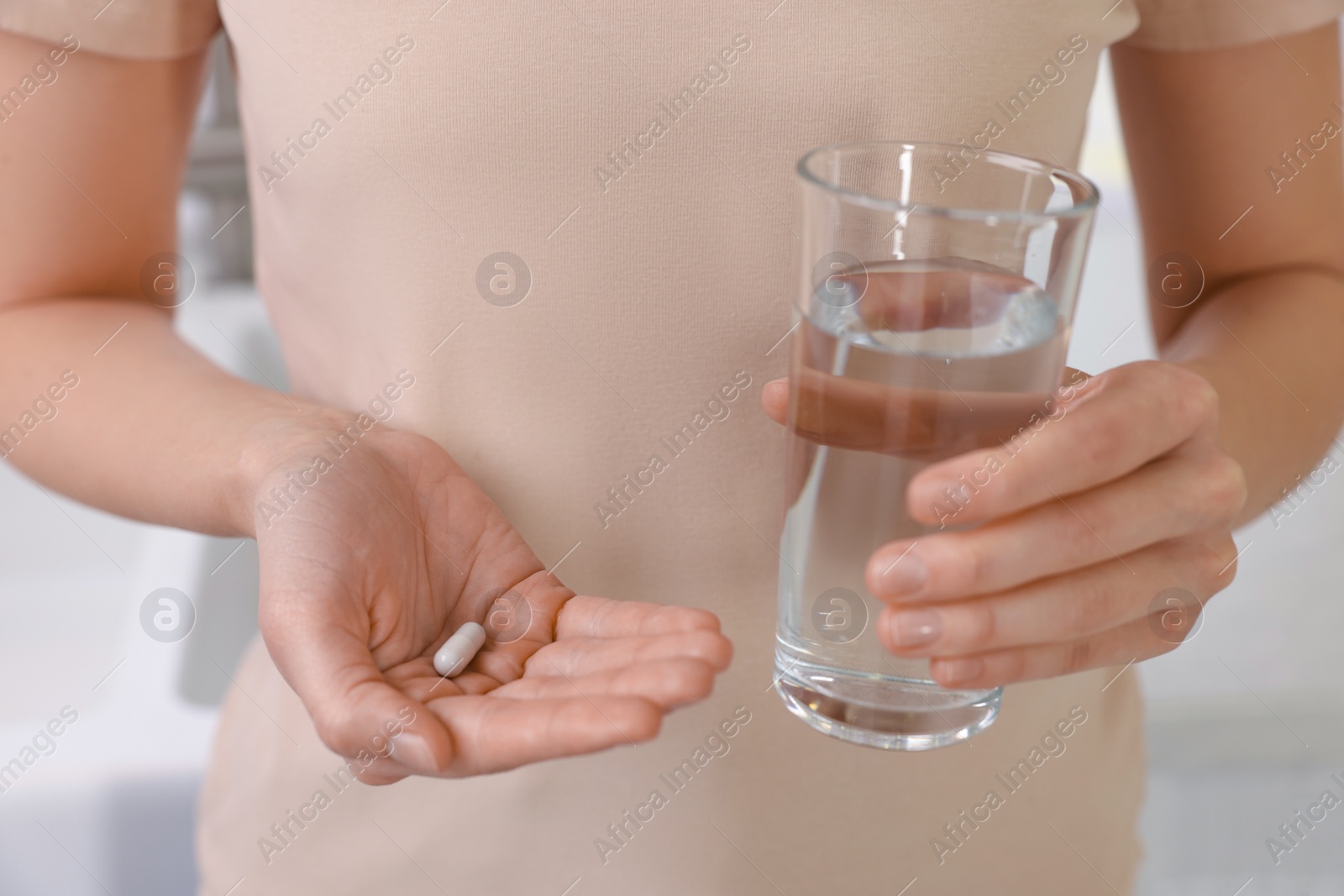 Photo of Beautiful young woman with vitamin pill and glass of water, closeup