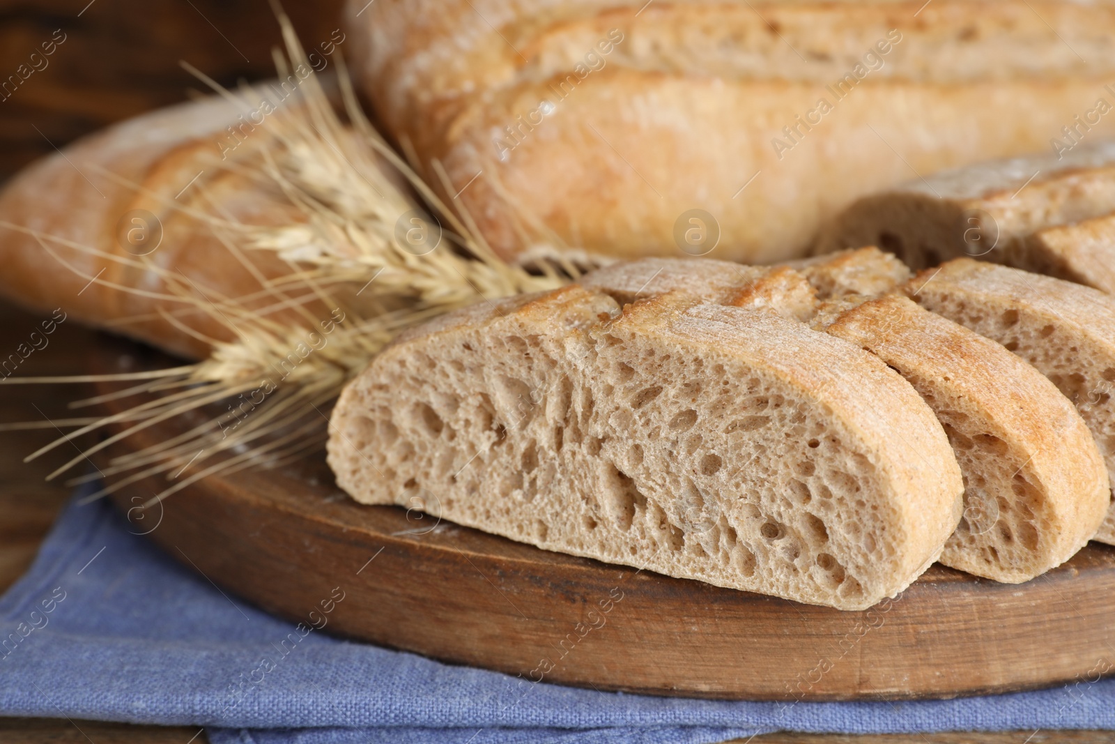 Photo of Cut delicious ciabatta on wooden board, closeup