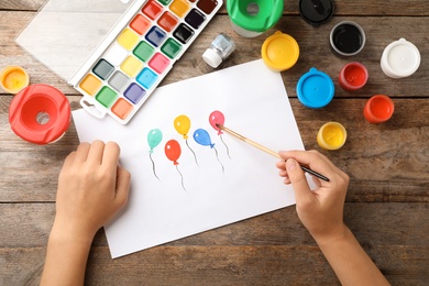 Photo of Girl painting picture of balloons on table, top view