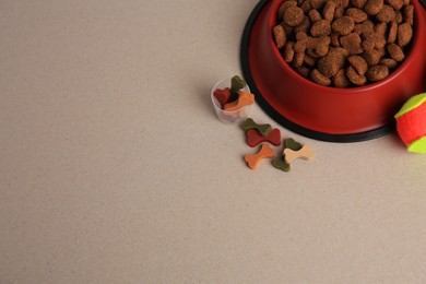 Photo of Vitamins, toy ball and dry pet food in bowl on beige background. above view. Space for text