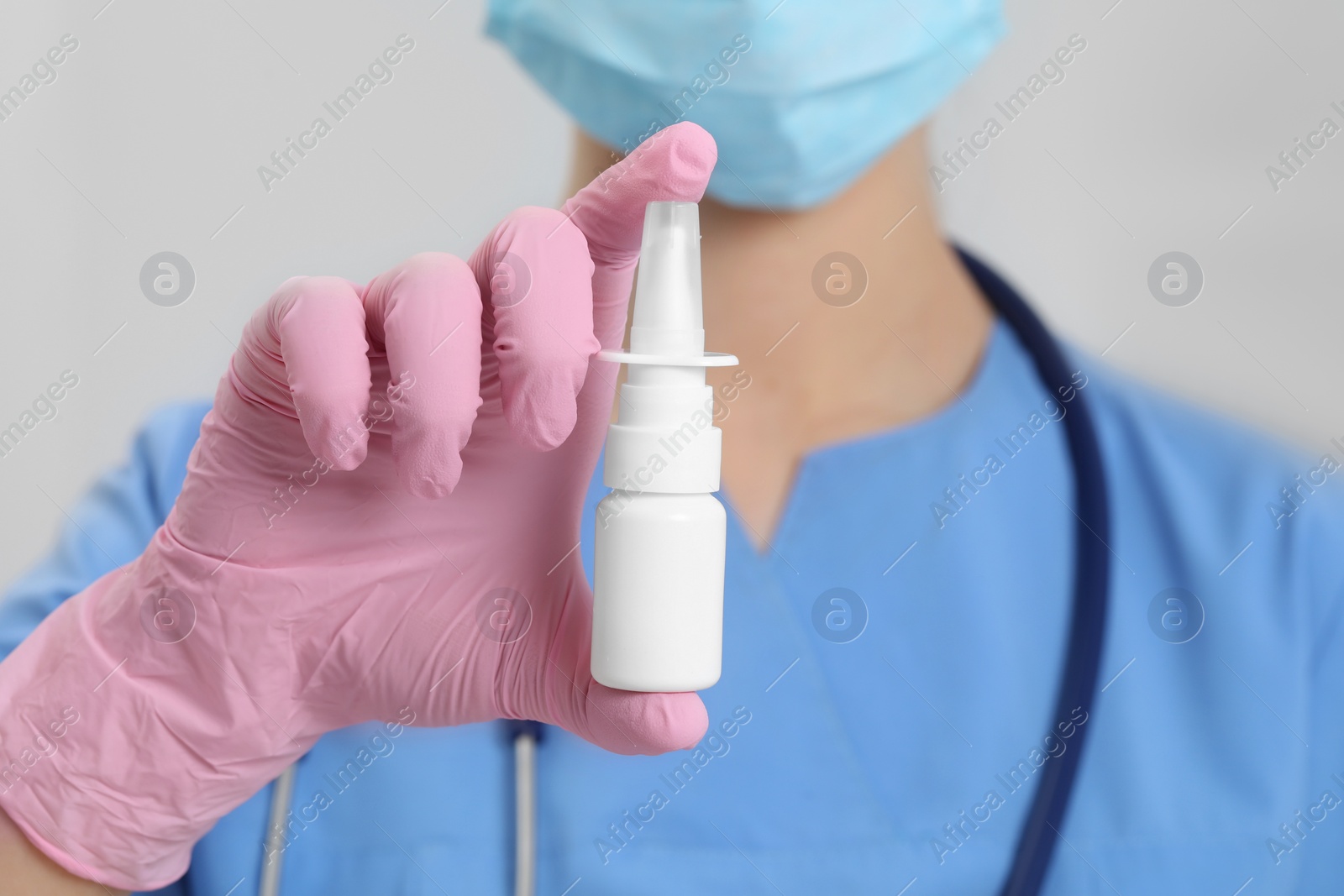 Photo of Doctor holding nasal spray on white background, closeup