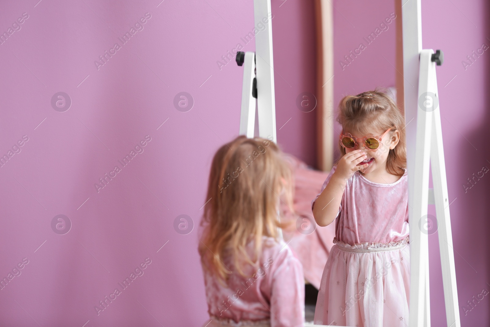 Photo of Cute little girl in princess dress near mirror at home