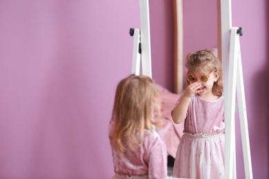 Photo of Cute little girl in princess dress near mirror at home