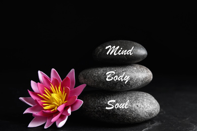 Stones with words Mind, Body, Soul and lotus flower on black background. Zen lifestyle