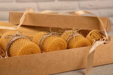 Photo of Beautiful yellow beeswax candles and sheets in box, closeup