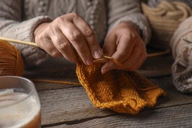 Photo of Woman knitting at wooden table, closeup. Creative hobby