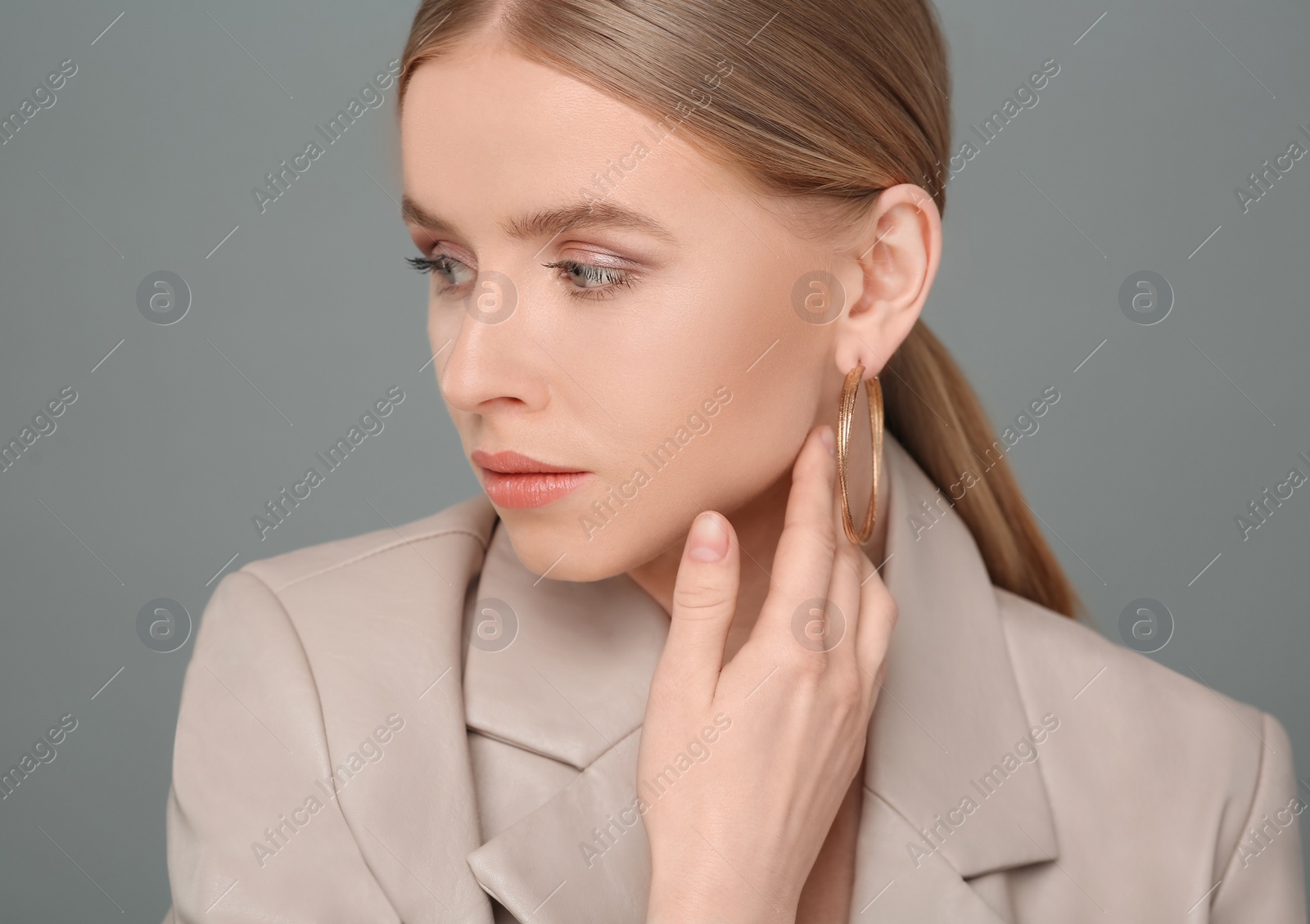 Photo of Beautiful young woman with elegant earrings on gray background