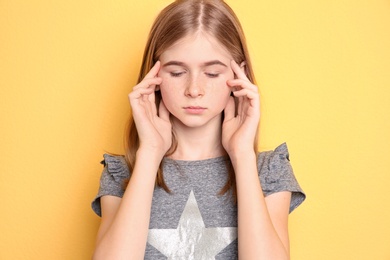 Photo of Teenage girl suffering from headache on color background