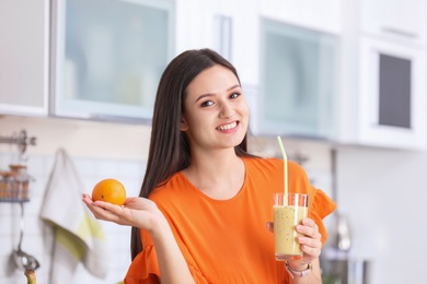 Photo of Young woman with glass of tasty healthy smoothie in kitchen