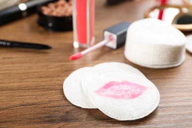 Photo of Dirty cotton pads and cosmetic products on wooden table, closeup