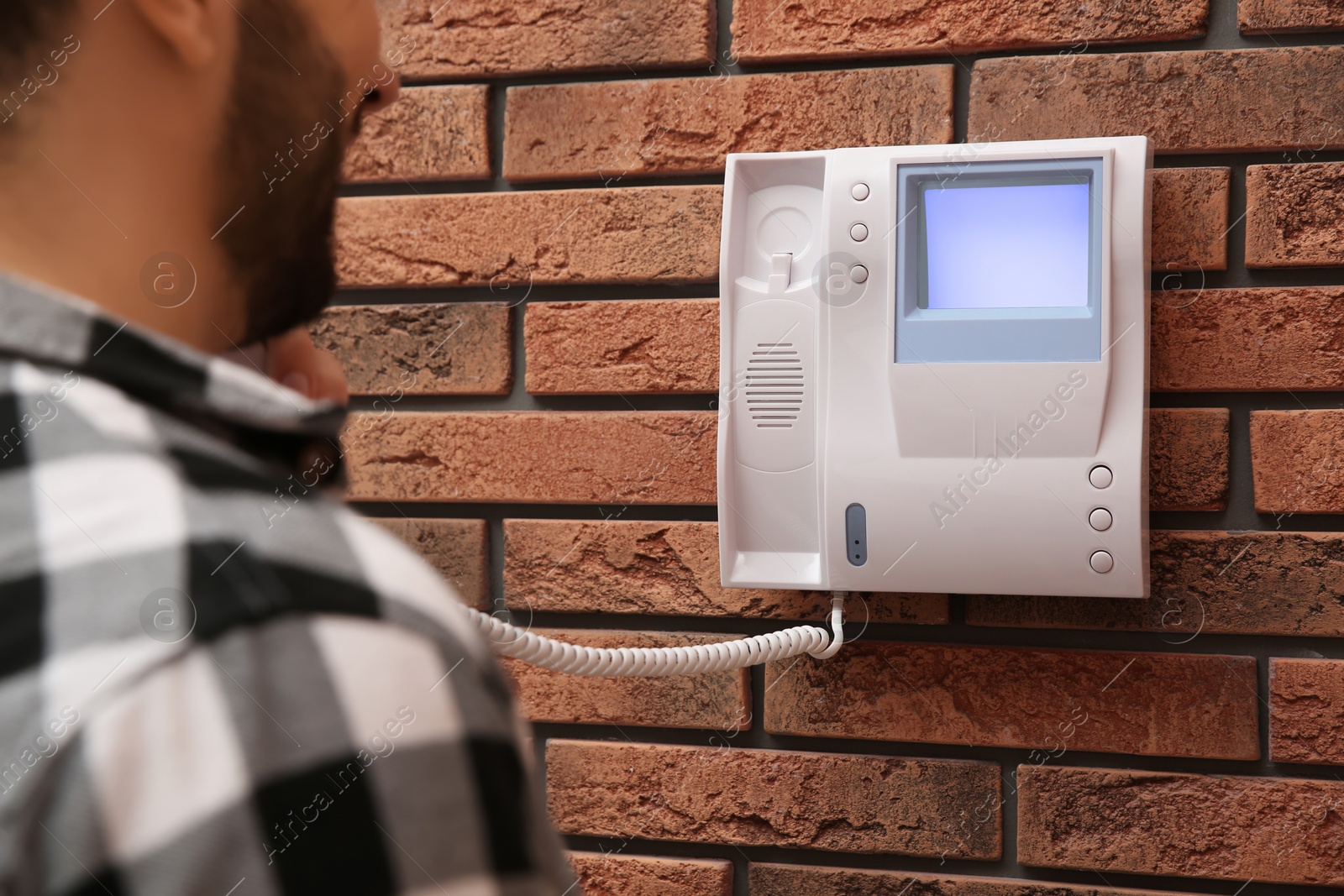 Photo of Man answering intercom call at home, closeup