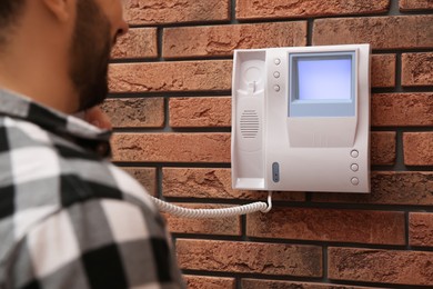 Man answering intercom call at home, closeup