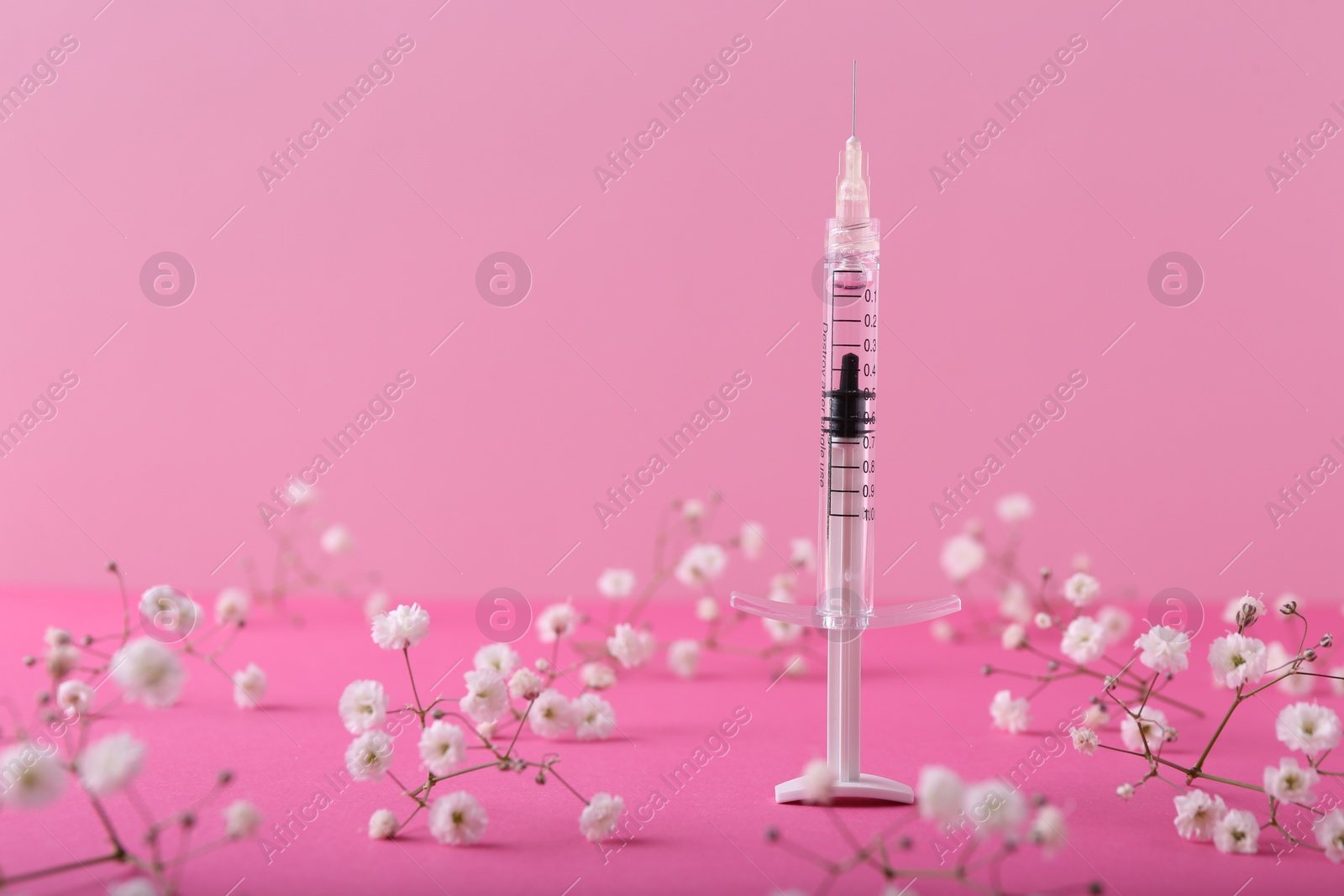 Photo of Cosmetology. Medical syringe and gypsophila flowers on pink background, space for text