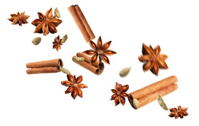Aromatic anise stars, cinnamon and cardamom falling on white background