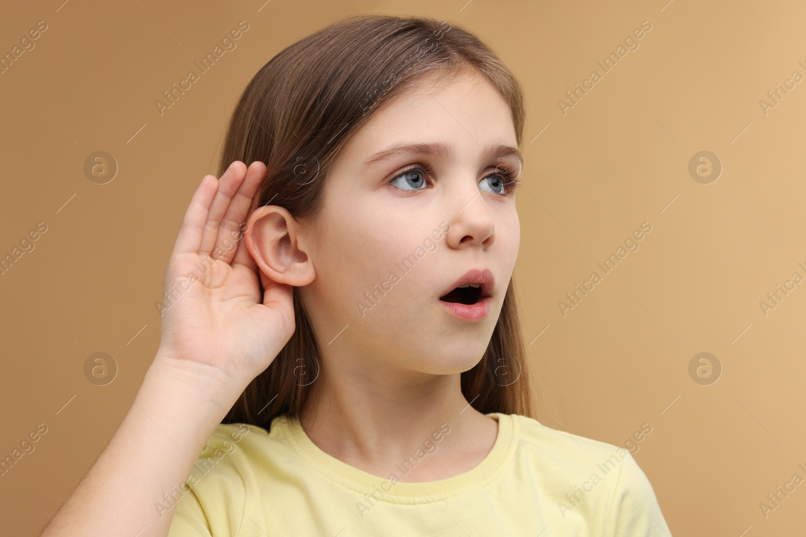 Photo of Little girl with hearing problem on pale brown background