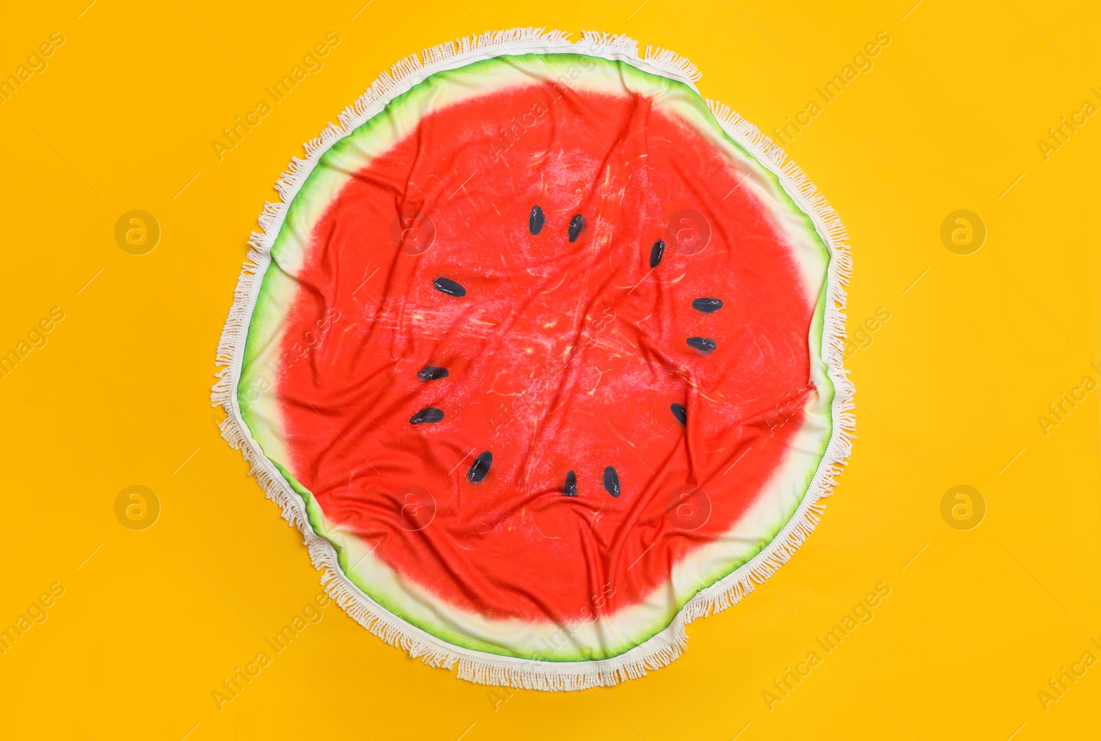 Photo of Crumpled round watermelon beach towel on yellow background, top view