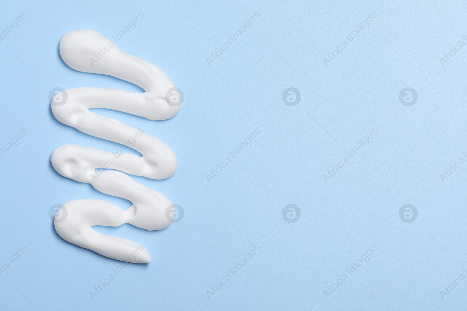 Photo of Sample of shaving foam on light blue background, top view. Space for text