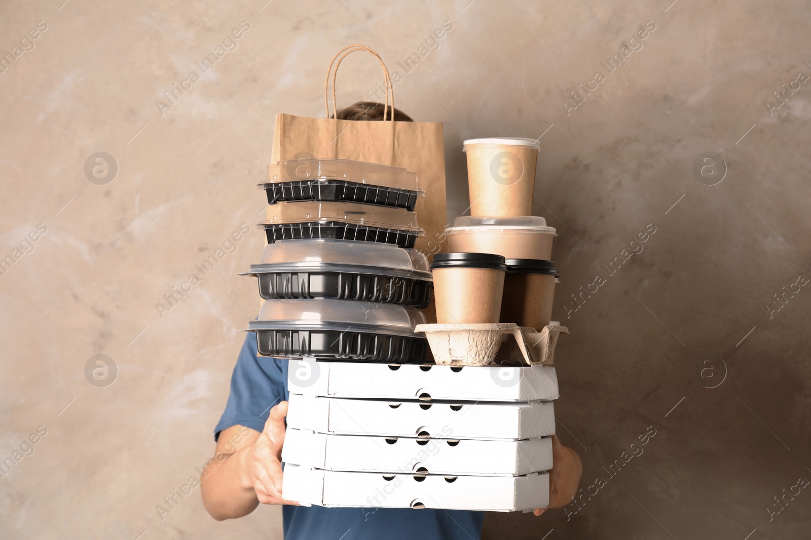 Photo of Courier with stack of orders on beige background. Food delivery service