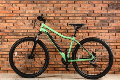 Photo of Modern bicycle near brick wall indoors. Healthy lifestyle